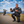 Motorcycle rider holding and pointing to the MotoPressor SmartPUMP cordless tyre inflator beside his adventure motorcycle