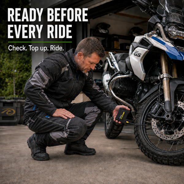 Motorcycle rider checking tyre pressure with a MotoPressor SmartPUMP cordless tyre inflator before a ride